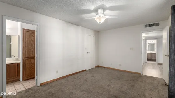 an empty room with chandelier fan and windows