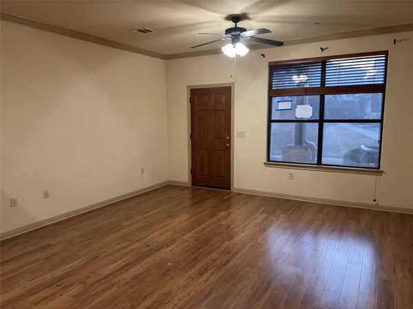 a view of an empty room with a window and wooden floor