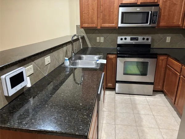 a kitchen with stainless steel appliances granite countertop a stove a microwave and a sink