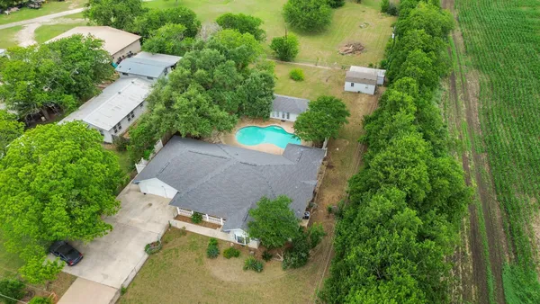 an aerial view of a house with a yard and trees all around