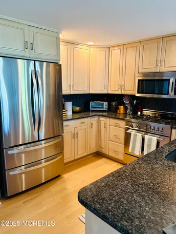 a kitchen with stainless steel appliances granite countertop a refrigerator a stove a sink and white cabinets