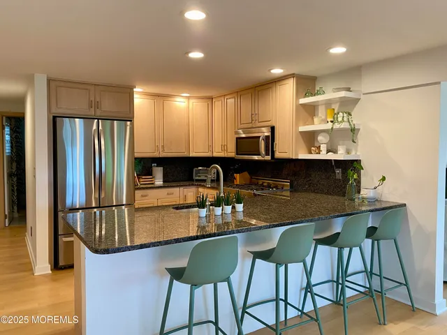 a kitchen with kitchen island granite countertop a table chairs microwave and refrigerator