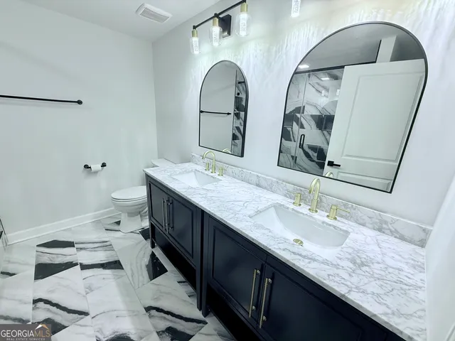 a bathroom with a granite countertop double vanity sink and mirror