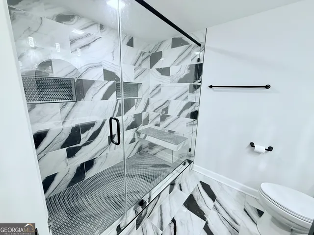 a bathroom with a granite countertop sink toilet and shower