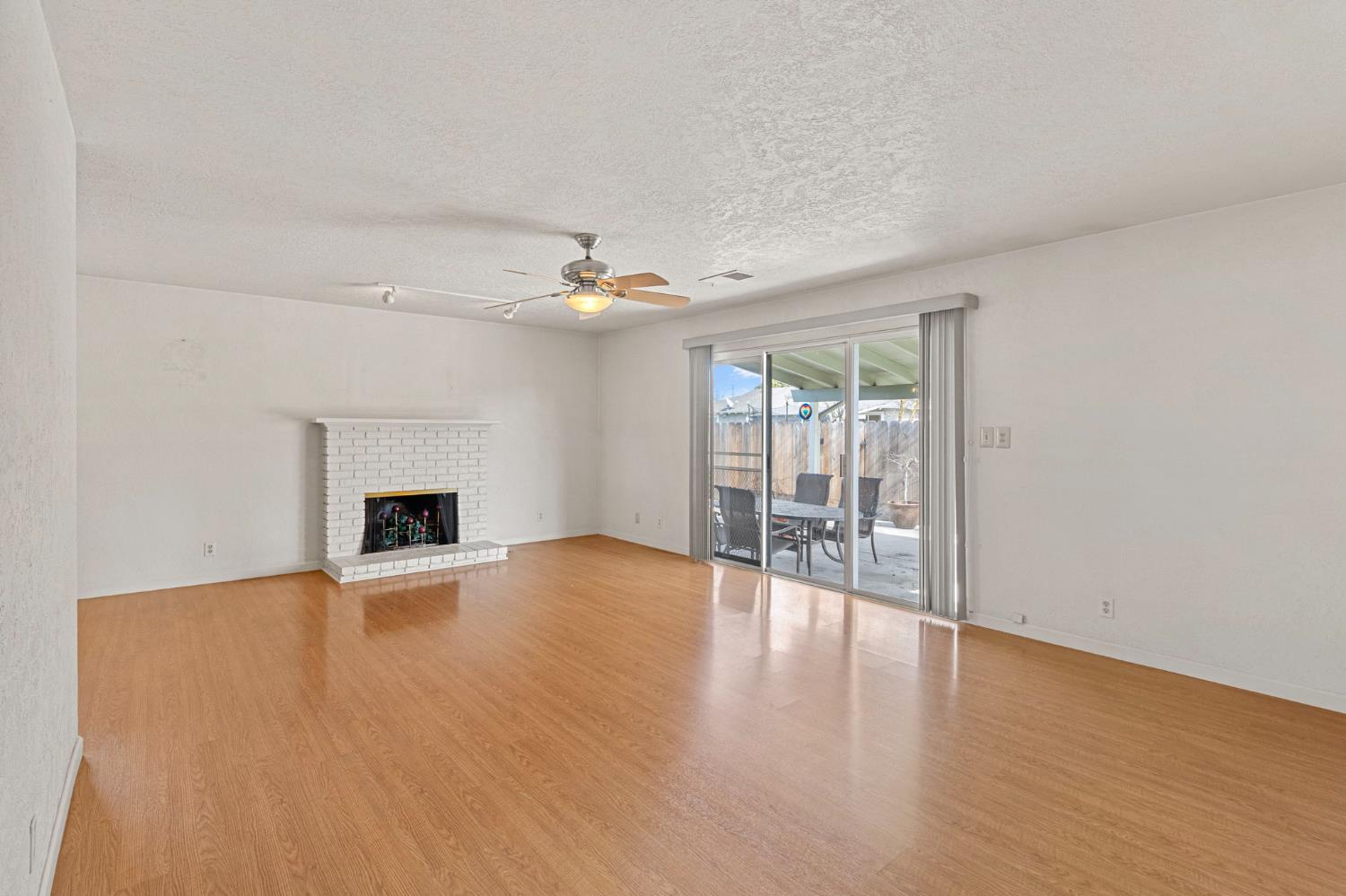 1428 Kent Way Modesto, CA 95355 - Photo 12 of 27 The large living room features a fireplace and sliding doors that lead to a covered patio and the sparkling pool.
