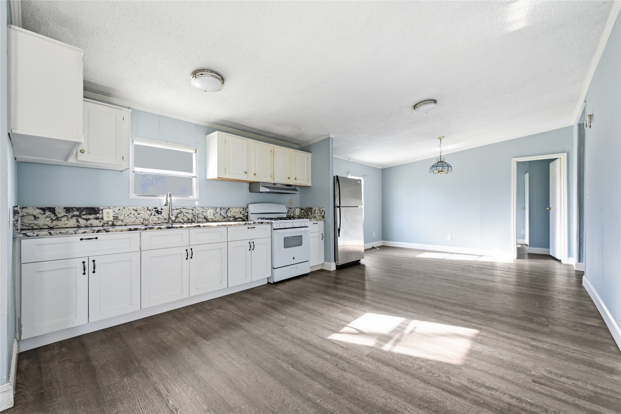 39512 Donigan Road Brookshire, TX 77423 - Photo 1 of 15 a kitchen with granite countertop a stove a sink and white cabinets with wooden floor