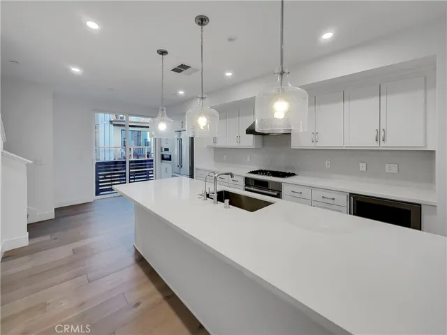 a large kitchen with kitchen island a stove a sink a center island and wooden floor