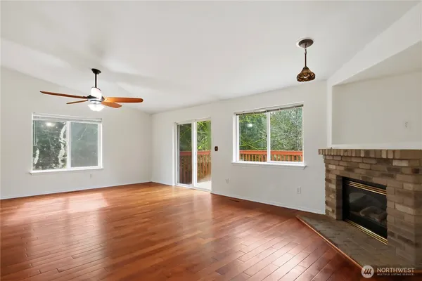 a view of an empty room with wooden floor fireplace and a window