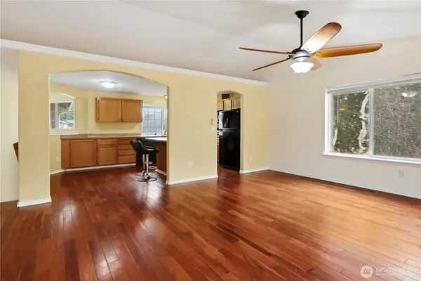 a view of empty room with wooden floor and fan