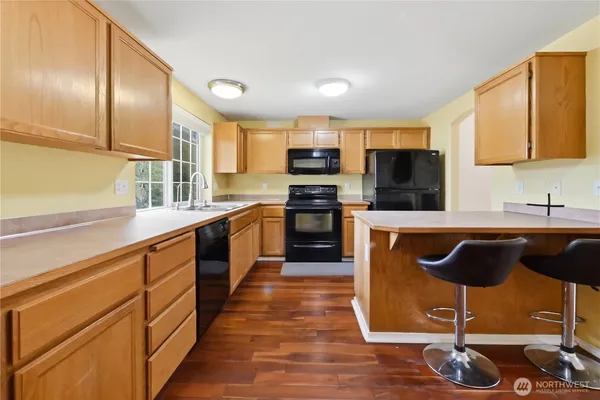 a large kitchen with stainless steel appliances granite countertop a stove a sink dishwasher and a microwave oven with cabinets