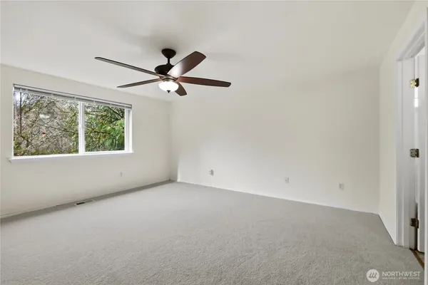 an empty room with a window and a fan