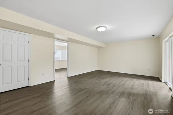 a view of an empty room with wooden floor and closet