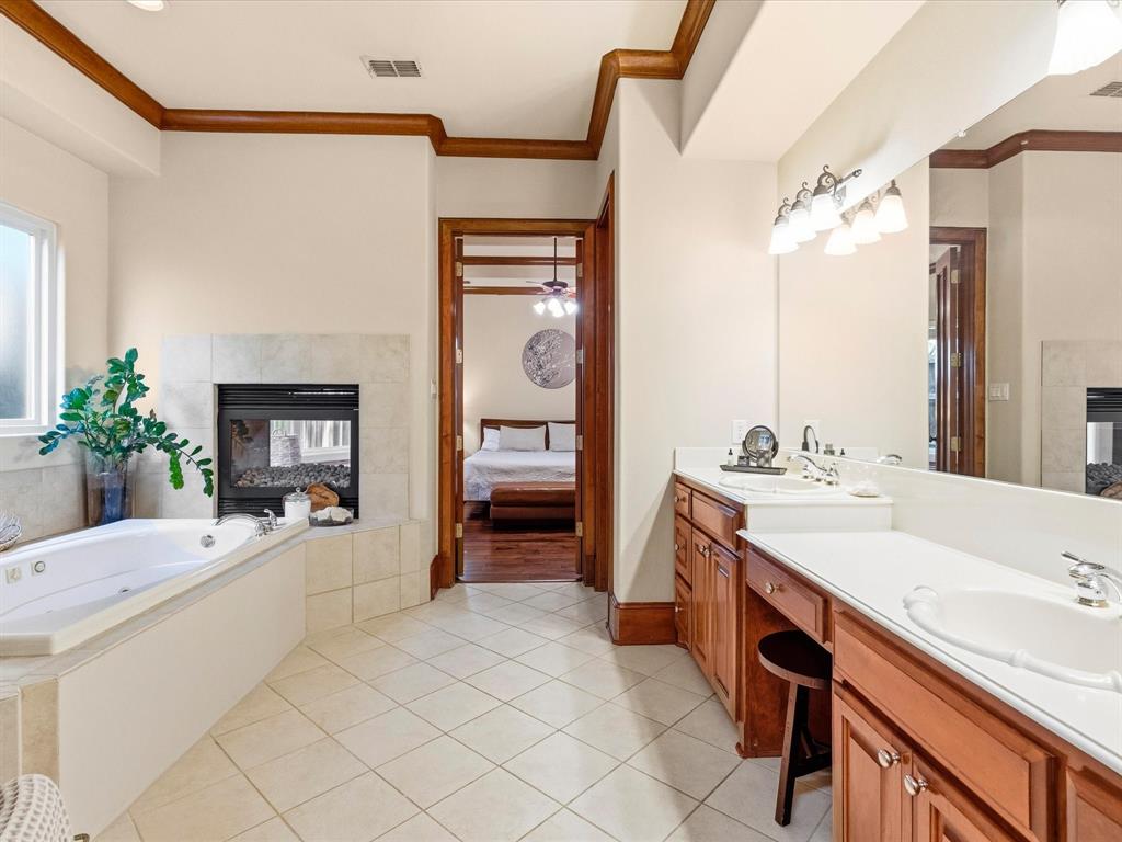 1615 Roma Lane Allen, TX 75013 - Photo 17 of 36 Spacious bathroom featuring a built-in jetted tub, fireplace with tile surround, and dual vanity with integrated sinks