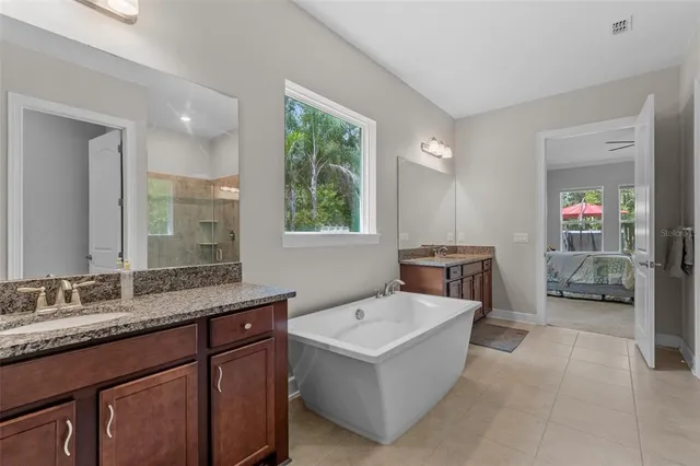 a en suite bathroom with a granite countertop tub double vanity and a mirror