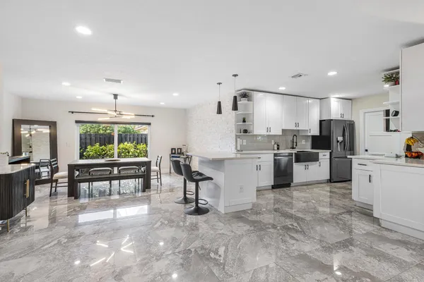 a large white kitchen with lots of counter space a sink appliances and a large window