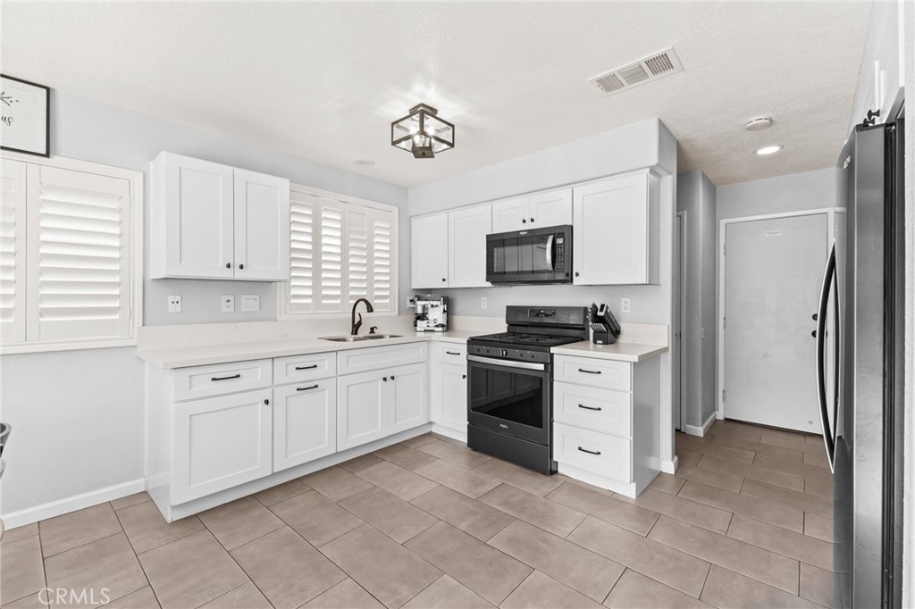 823 Pathfinder Way Corona, CA 92878 - Photo 18 of 59 a kitchen with granite countertop white cabinets stainless steel appliances and a window