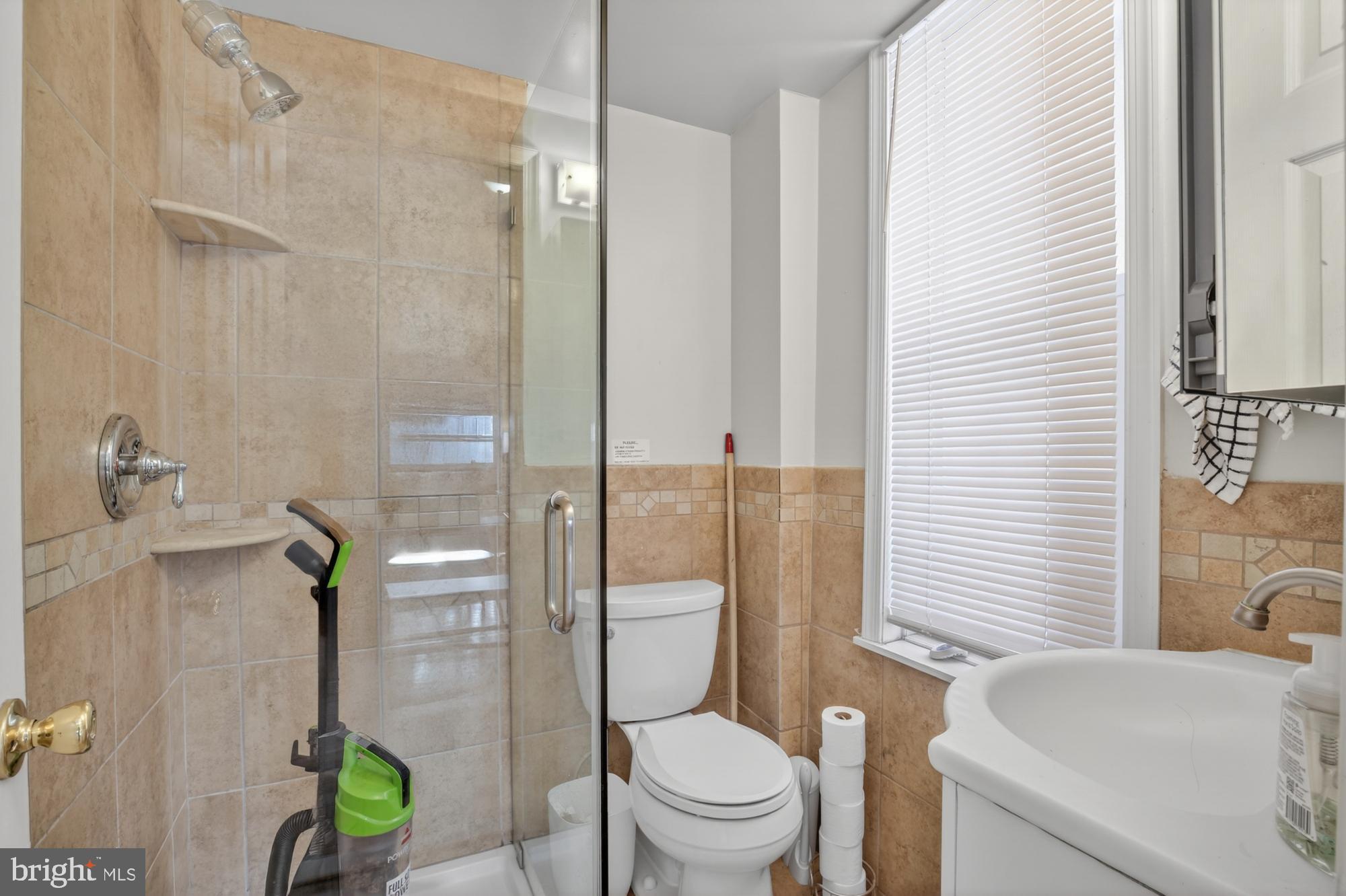 4058 Irving Street Philadelphia, PA 19104 - Photo 7 of 23 a bathroom with a granite countertop toilet a sink a shower and a mirror