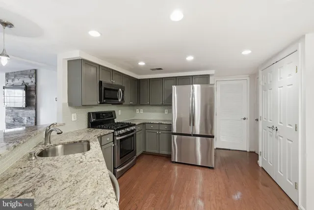 a kitchen with granite countertop stainless steel appliances a refrigerator a stove top oven a sink and a center island