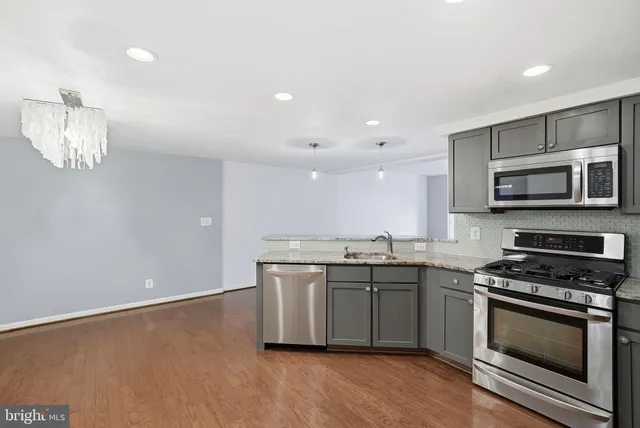 a kitchen with stainless steel appliances a sink a stove a microwave a sink a refrigerator and microwave