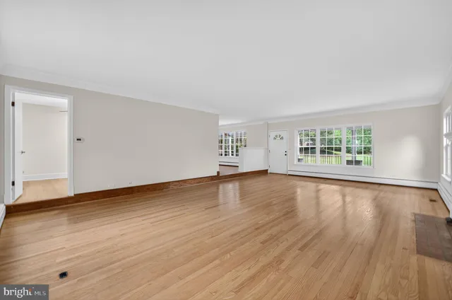 a view of an empty room with a window and wooden floor