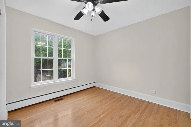 a view of empty room with wooden floor and fan