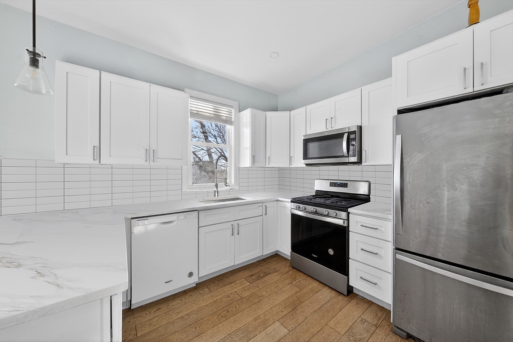 a kitchen with granite countertop white cabinets and stainless steel appliances