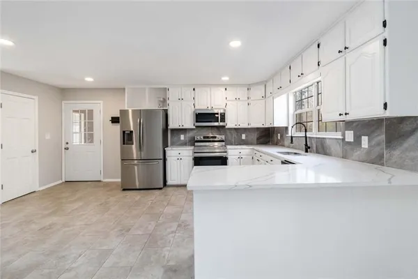 a kitchen with granite countertop white cabinets and white stainless steel appliances