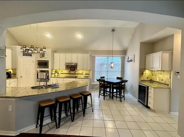 a dining hall with stainless steel appliances kitchen island granite countertop a dining table chairs and granite counter tops