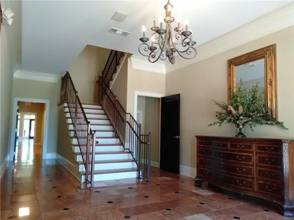 a view of a hallway with wooden floor and chandelier