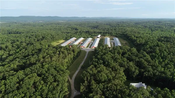 an aerial view of residential house with outdoor space and trees all around