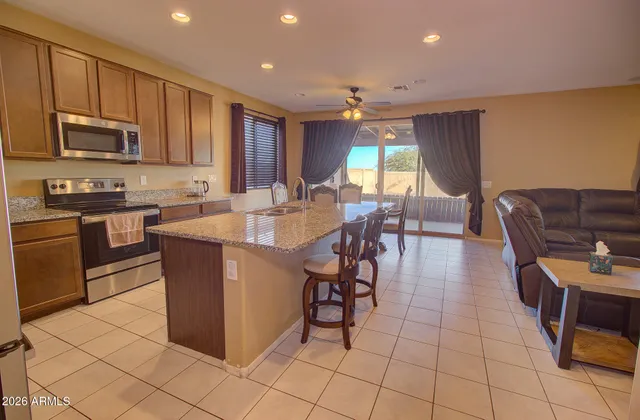 a large kitchen with stainless steel appliances granite countertop a stove a sink a dining table and chair