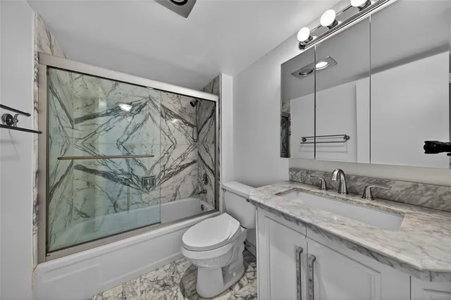 a bathroom with a granite countertop sink toilet and shower