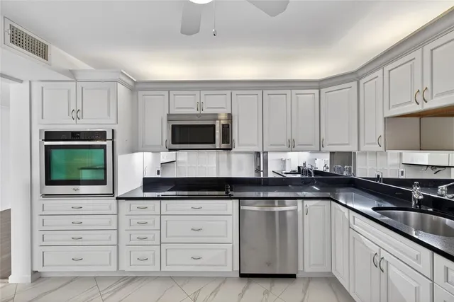 a kitchen with granite countertop white cabinets and stainless steel appliances