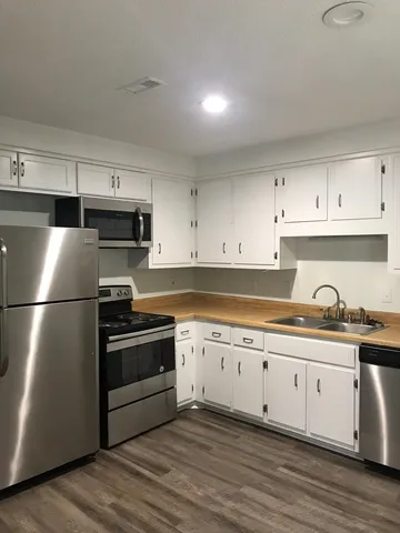 a kitchen with cabinets stainless steel appliances and wooden floor