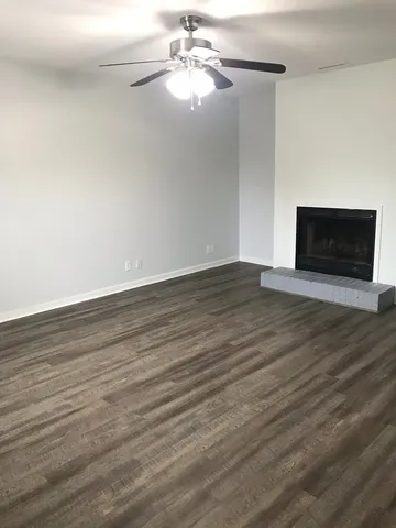 a view of an empty room with wooden floor fireplace and a window