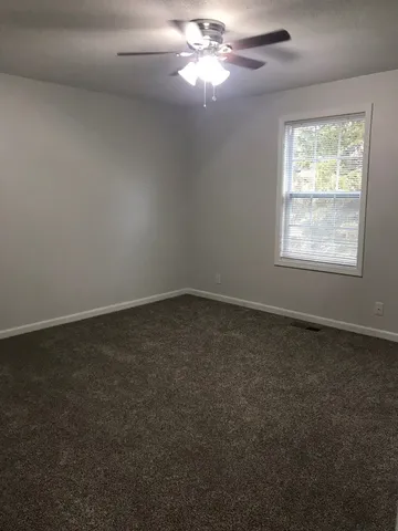 an empty room with windows and fan