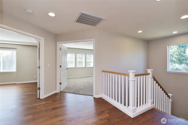a view of a hallway with wooden floor and windows