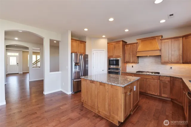 a large kitchen with stainless steel appliances granite countertop a large counter top a sink and a stove