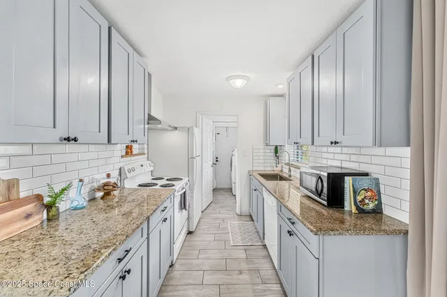 a large kitchen with stainless steel appliances granite countertop lots of counter top space and wooden floor