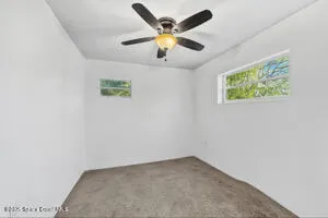 an empty room with ceiling fan and window