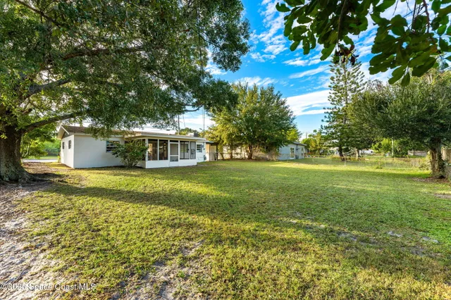 a view of a house with a big yard and large trees