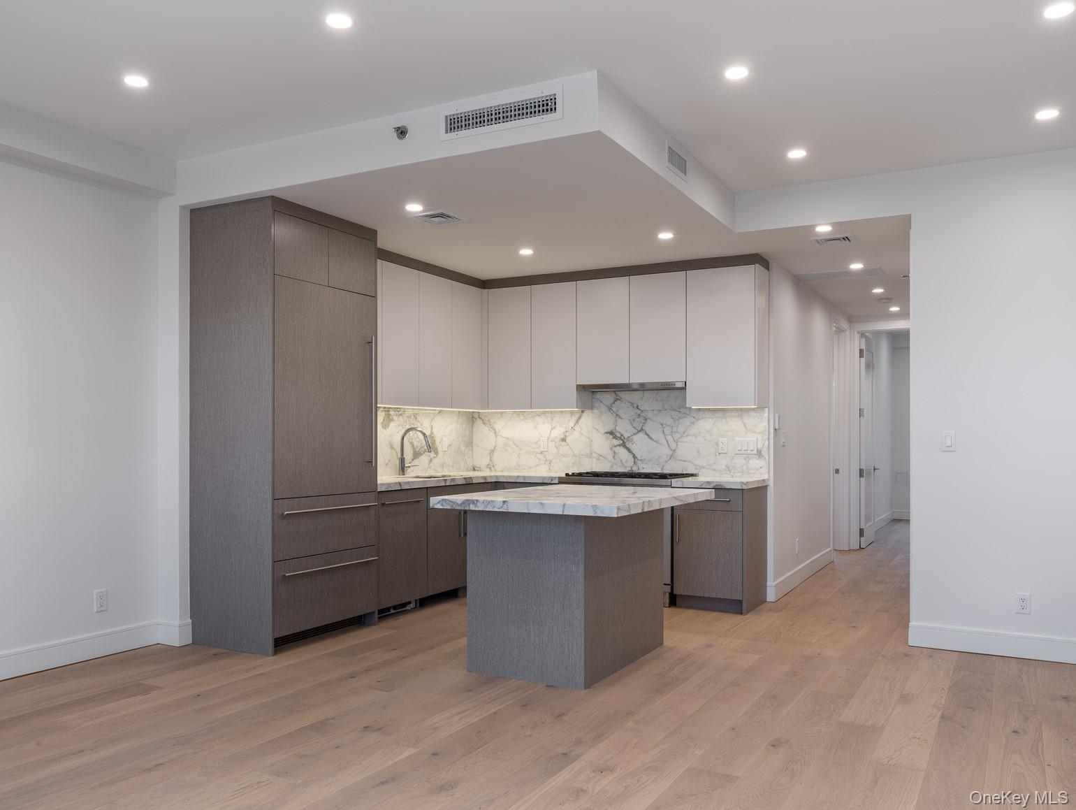 21-31 Shore Boulevard, Unit 1E Queens, NY 11105 - Photo 7 of 12 a kitchen with kitchen island granite countertop wooden cabinets and white stainless steel appliances