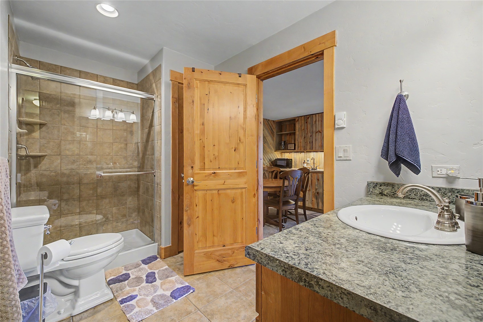 6726 Ryan Gulch Road, Unit 6726 Wildernest, CO 80498 - Photo 20 of 39 a bathroom with a granite countertop sink a toilet a mirror and shower