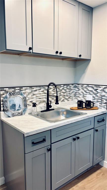 4603 Junius Street, Unit 8 Dallas, TX 75246 - Photo 6 of 16 Kitchen with gray cabinets, tasteful backsplash, light countertops, and light wood-style floors