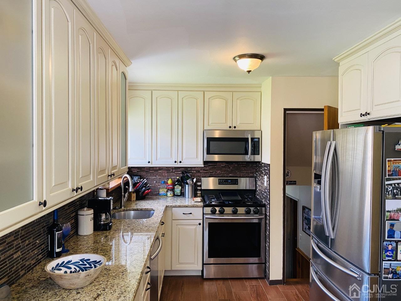 169 McFarlane Road Colonia, NJ 07067 - Photo 5 of 11 a kitchen with stainless steel appliances a stove a sink a refrigerator white cabinets and wooden floor