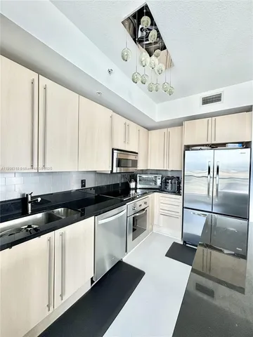 a kitchen with granite countertop a refrigerator a sink dishwasher a stove and white cabinets