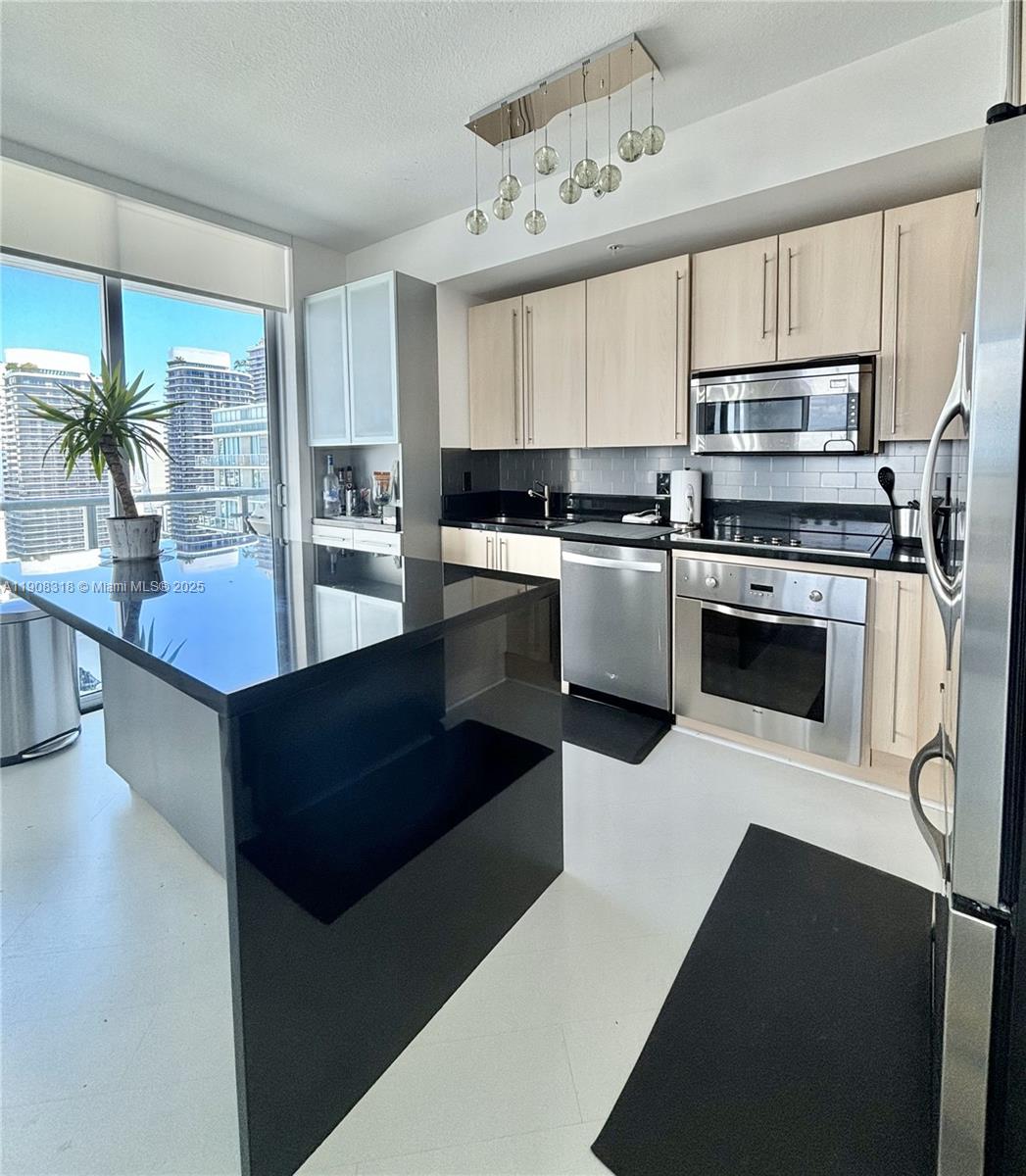 79 Southwest 12th Street, Unit 4012S Miami, FL 33130 - Photo 7 of 34 a kitchen with stainless steel appliances granite countertop a refrigerator a stove a sink dishwasher and white cabinets with wooden floor