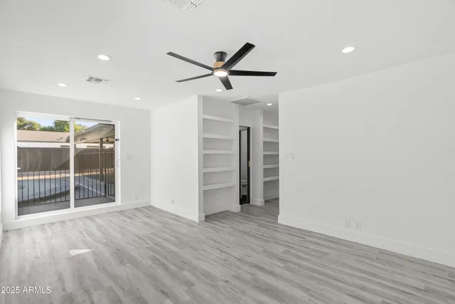 a view of an empty room with a window and wooden floor