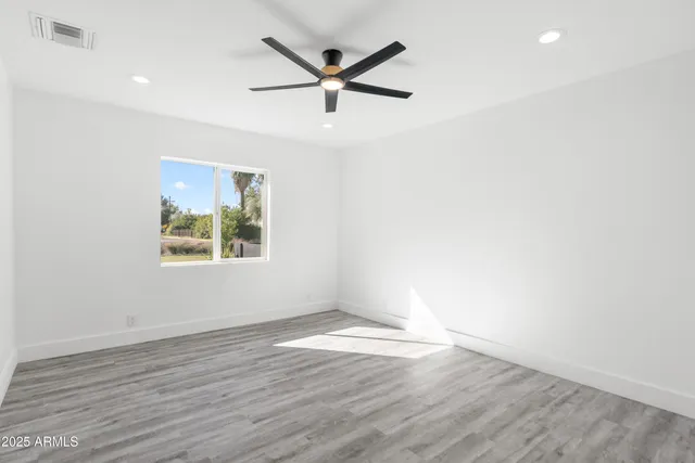 a view of empty room with wooden floor and fan