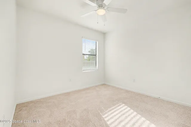 an empty room with a window and a fan